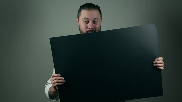 Casual beard man in shirt holding up a black cartboard to write something on it. News and business list or announce something