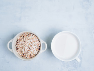 Oat milk drink in white cup and cereal flakes on kitchen bench. Flat lay. Copy space.