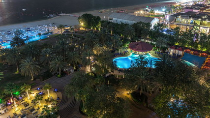 Fototapeta na wymiar Aerial view of beach and tourists walking in JBR with skyscrapers night timelapse in Dubai, UAE