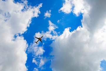 Fototapeta na wymiar Big grey passenger plane in the blue cloudy sky, summer