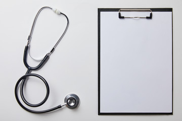 top view of stethoscope near clipboard with blank paper isolated on whtie