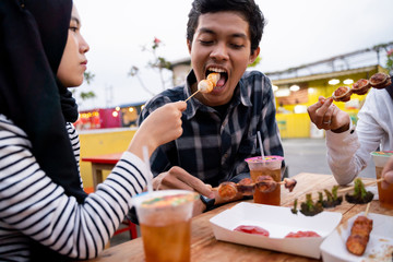 Group of young friends enjoying meal in outdoor cafe on the building rooftop