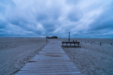 Holzsteg am Meer mit Sandstrand und Gewitterwolken