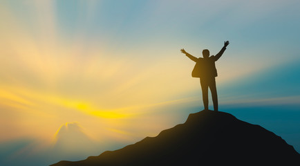 silhouette of man on mountain top over sky and sun light background,business, success, leadership, achievement and people concept