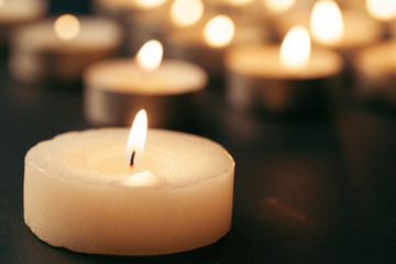 Burning candle on table in darkness, space for text. Funeral symbol