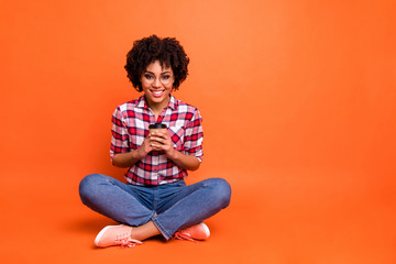 Full body photo funny lady sit floor hold hands paper coffee mug rest adorable amazing wear specs casual checkered plaid shirt isolated orange background