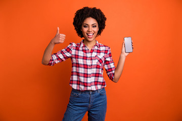 Photo of amazing wavy model lady hold hands telephone thumb up symbol approve cool quality wear casual checkered shirt isolated orange background