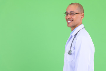 Closeup profile view of happy bald multi ethnic man doctor looking at camera