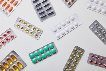 top view of scattered blister packs with different pills isolated in white