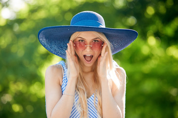 Wow effect. Fashionably dressed woman in vacation. Wearing stylish blue dress, straw hat and bracelet. Straight long blond hair. Summer Sale concept