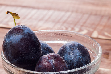 Fresh plums on wooden table background. Half of blue plum fruit. Many beautiful plums with...