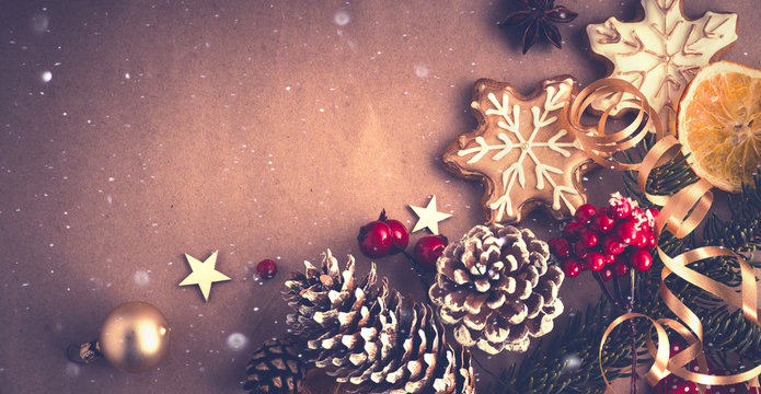 Christmas dark background border in bright Golden brown tones. Fir branches, cones, gingerbread cookies, serpentine and .red berries on textured background with copy space