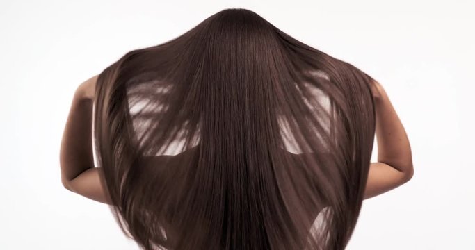 Woman moves long hair. Rear view. Girl shakes long straight hair. Slow motion footage. Rear view. 4k. Female model is fluttering hair. Ginger. Red haired.
