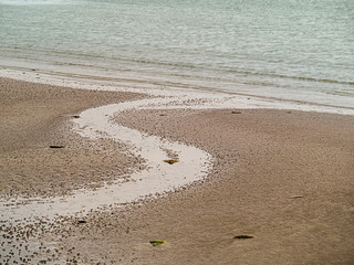 S shaped stream flows water into ocean, Calm muted colors. simple landscape background.