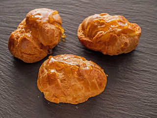 Three small eclairs with sweet syrup on a slate plate, Concept: dessert, pastry,