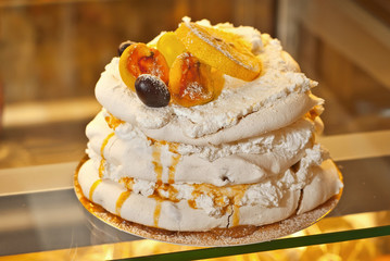 Round cake with a yellow filling in a shop window. Dried fruits and oranges on the cake.