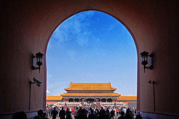 People passing through one of the internal red colored gates of the Palace Museum, known as the...