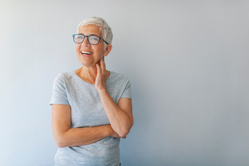 Beautiful senior woman in front of grey background.  Portrait of business woman with glasses smiling. Happy senior woman. Isolated. Portrait of mature woman with eyeglasses on grey background