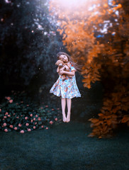 dream of cute girl with flying hair hovers above ground with teddy bear in hands. Little Princess in long light dress levitates in dreams and hugs toy, creative magical photo in air