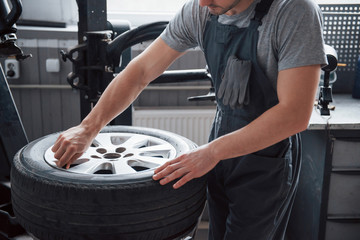 Young man works with wheel's disks at the workshop at daytime