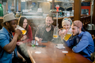 Group of five friends men women met in cafe, smoking shisha hookah, drinking beer, chatting.