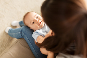 babyhood, family and motherhood concept - young mother with little asian baby son at home