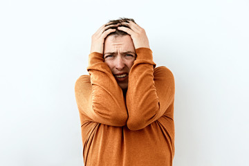 Fear,Shame and shy emotion. Portrait of  Young man in orange sweater,against white background