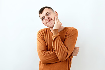  Thoughtful, thinking emotion concept. Young man in orange color sweater,face portrait on white backgound.