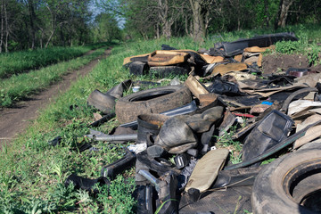 A pile of garbage auto parts in the forest.