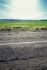 Old road with a dividing strip, grass and sky in the background.