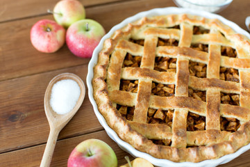 food, culinary and baking concept - close up of apple pie with sugar on wooden table