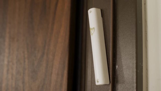 Slow pan over a Mezuzah set on house entrance