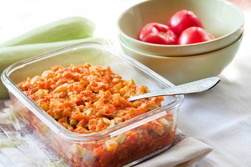 Squash stew with carrot and tomatoes in a square glass dish