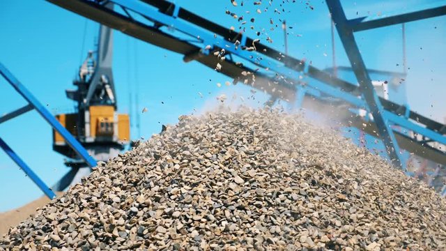 A pile of crushed stone near a crushing machine. Industrial mining concept.