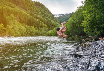 man jumps into a mountain river