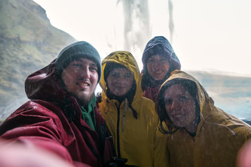 four friends make a selfie under an Icelandic waterfall