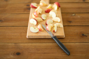 fruits, food cooking and eating concept - sliced apples and kitchen knife on wooden cutting board