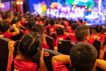 Children sitting on seats in the theater watching the performance