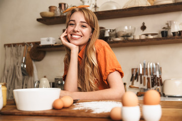 Happy cheerful smiling young blonde girl chef cooking at the kitchen.