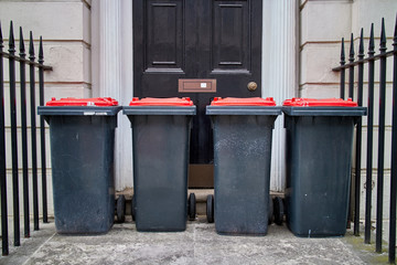 Four wheelie bins stood outside a front door. - obrazy, fototapety, plakaty