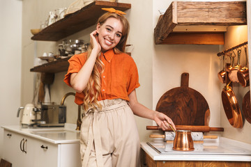 Happy cheerful young blonde girl chef at the kitchen cooking.