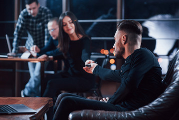 Give me the phone. Team of young business people works on their project at night time in the office