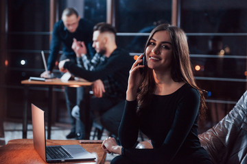 Charmful positive woman. Team of young business people works on their project at night time in the office