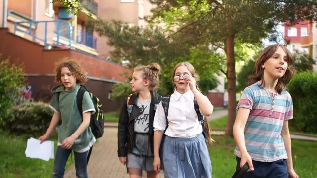 Children returning from school, fun running, throwing up school bags and notebooks. The end of the school year, the beginning of the summer holidays, back to school