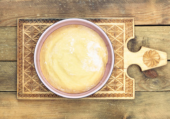 Dough in a pink bowl  on handmade wooden cutting board on rustic rough wooden table,overhead top view, flat lay, closeup, homemade bread cooking concept