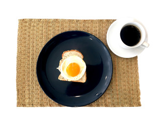 Breakfast setting with hot black coffee and fried egg topping on wholewheat bread put on straw mat isolated on white background.