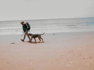 Active mid-adult woman walking with her dog on the beach. Free time fun moments.