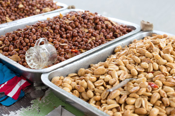 Roasted, salted peeled and unpeeled, crude peanuts on metal trays on the street market in the Philippines