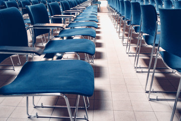 An empty large lecture room with blue chairs..