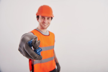 Take this tool. Man in orange colored uniform stands against white background in the studio